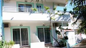 A two-story building with a balcony, large windows, and a small garden area. - Marianthi Studios Stegna (Rhodes)