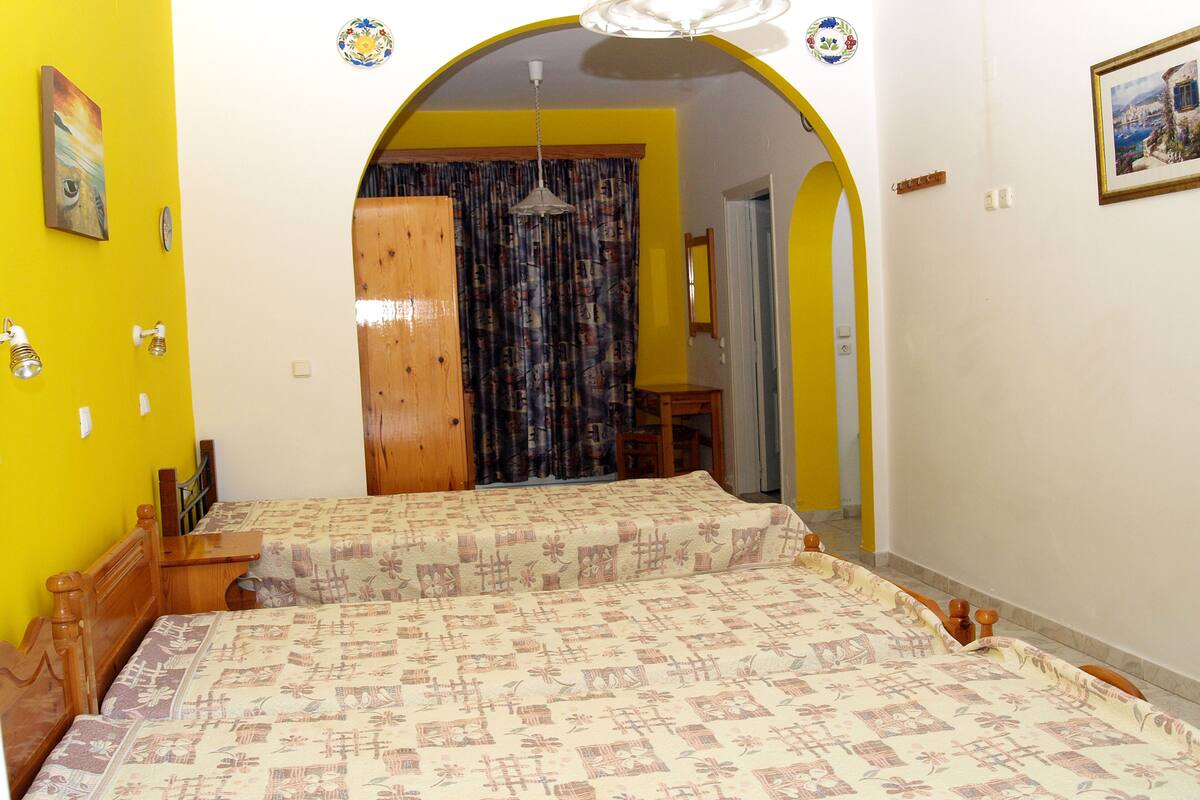 Una habitación con cama, cabecero de madera y cortina estampada.