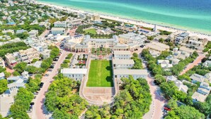 Luftaufnahme einer Küstenwohngegend mit einem großen zentralen Gebäude, einem Strand und freiem Blick auf den Ozean.