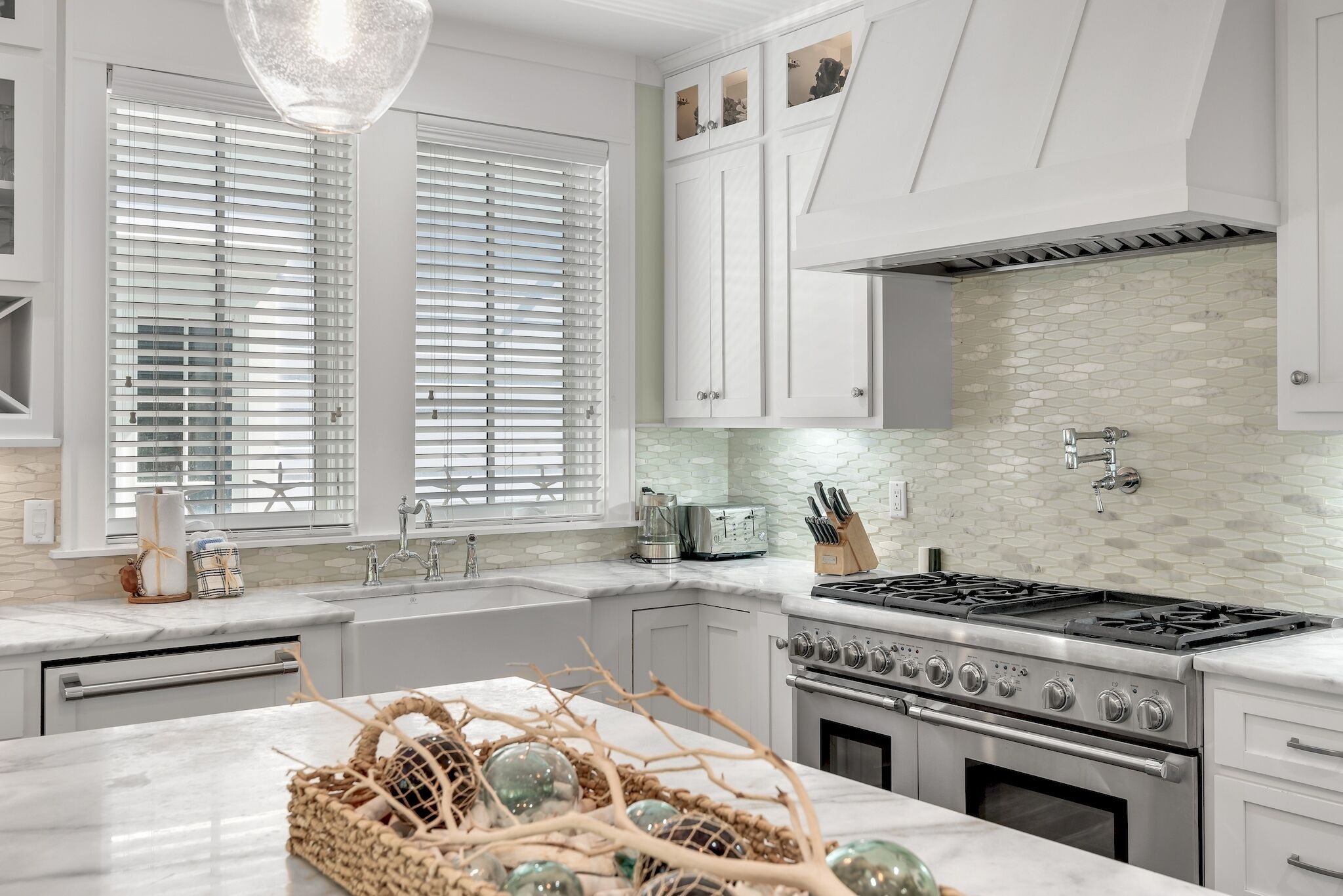 Una cocina moderna con muebles blancos, estufa a gas y salpicadero de azulejos.