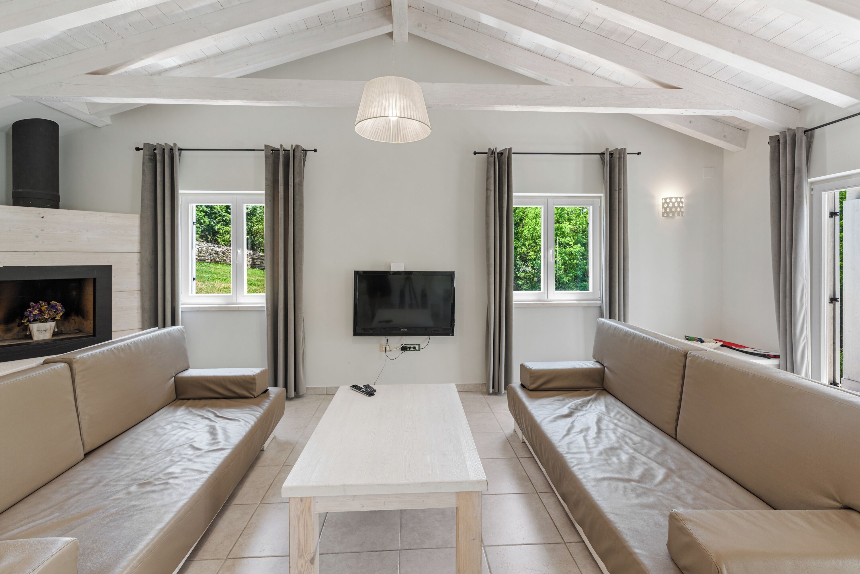 A modern living room with a white sofa set, a television, and a fireplace.