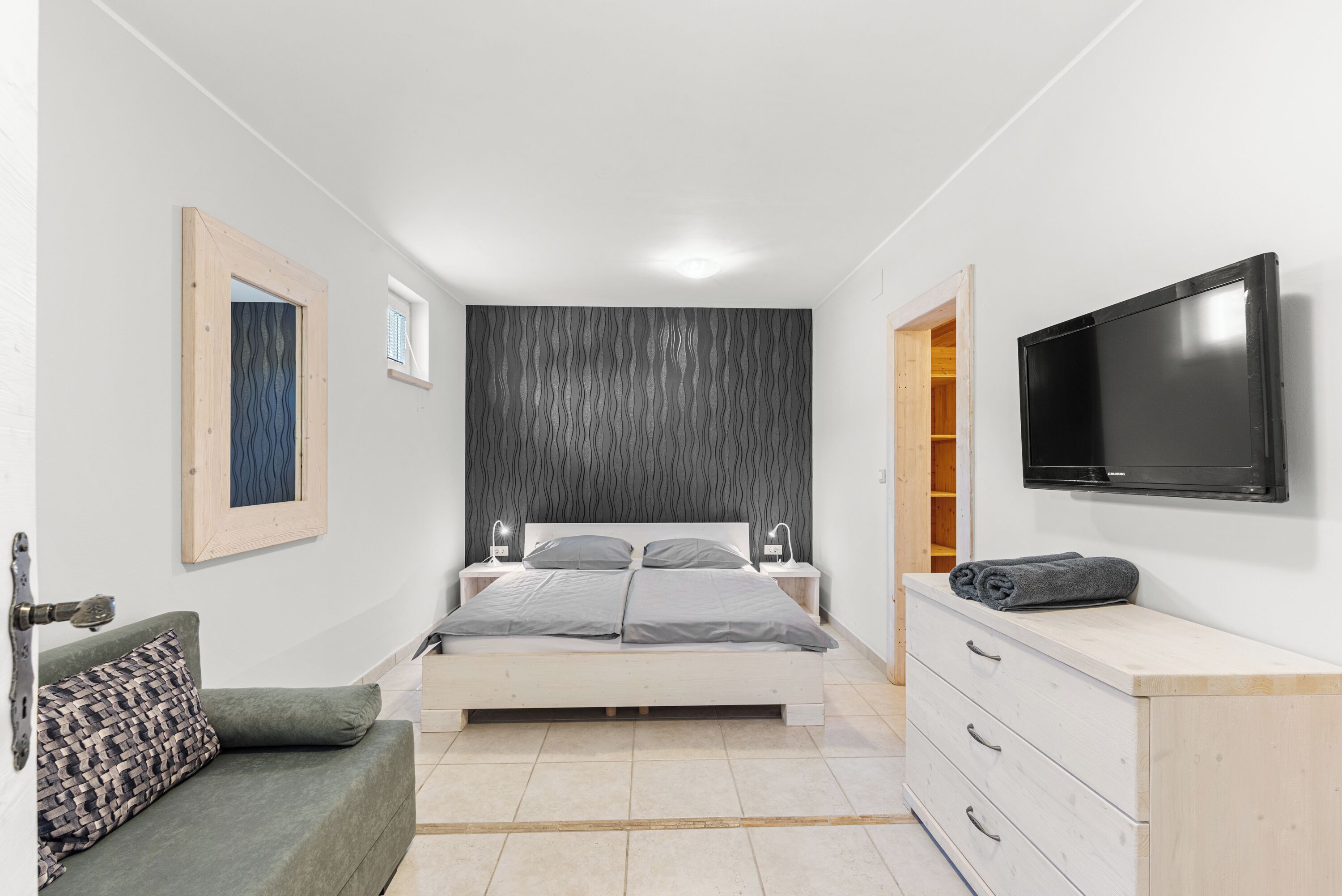 A bedroom with a bed, a dresser, a television, and a window.