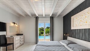 Une chambre à coucher comprenant un lit, une commode, une chaise, un miroir et donnant sur une piscine.