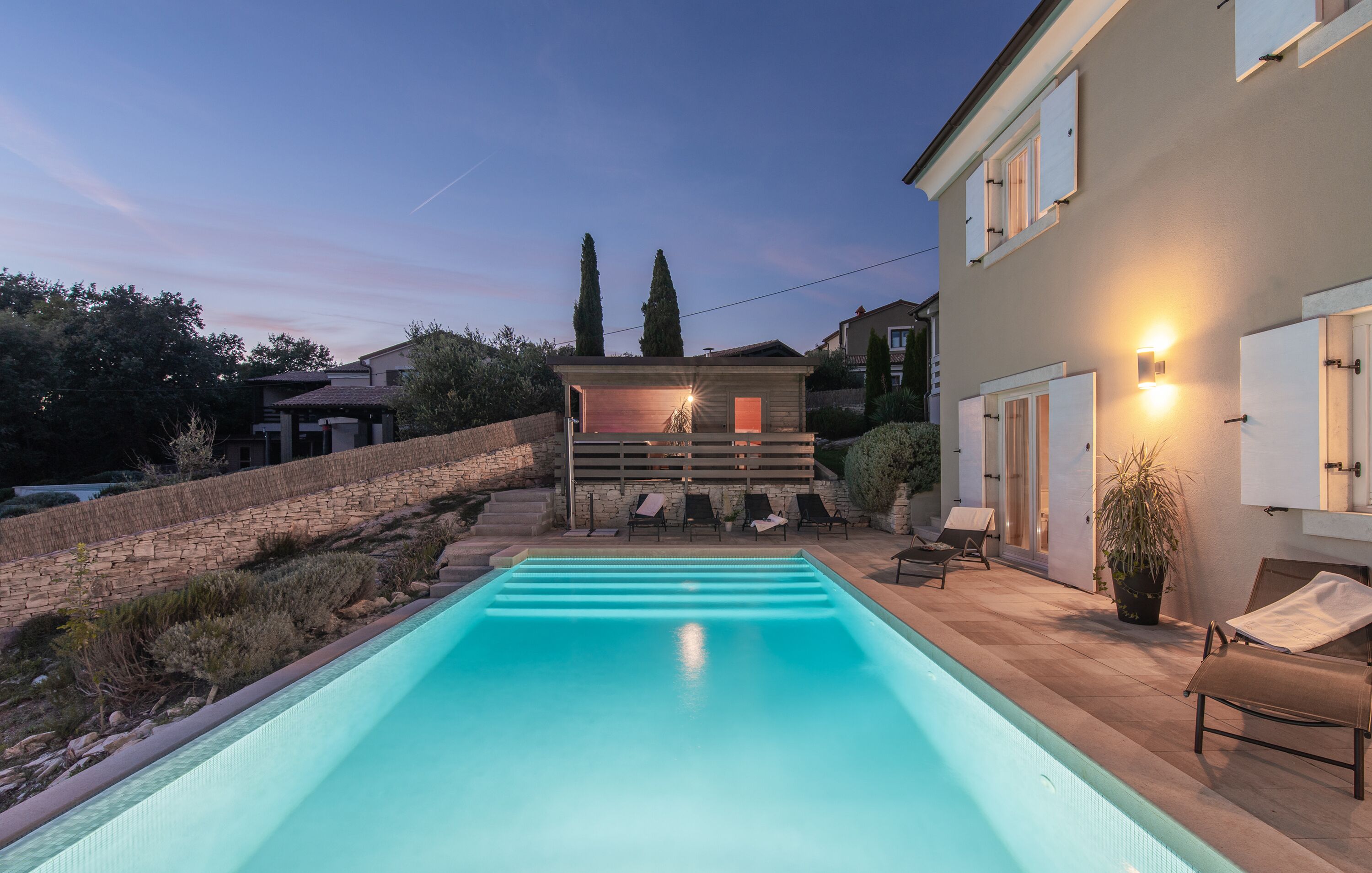 A swimming pool with lounge chairs and a covered seating area.