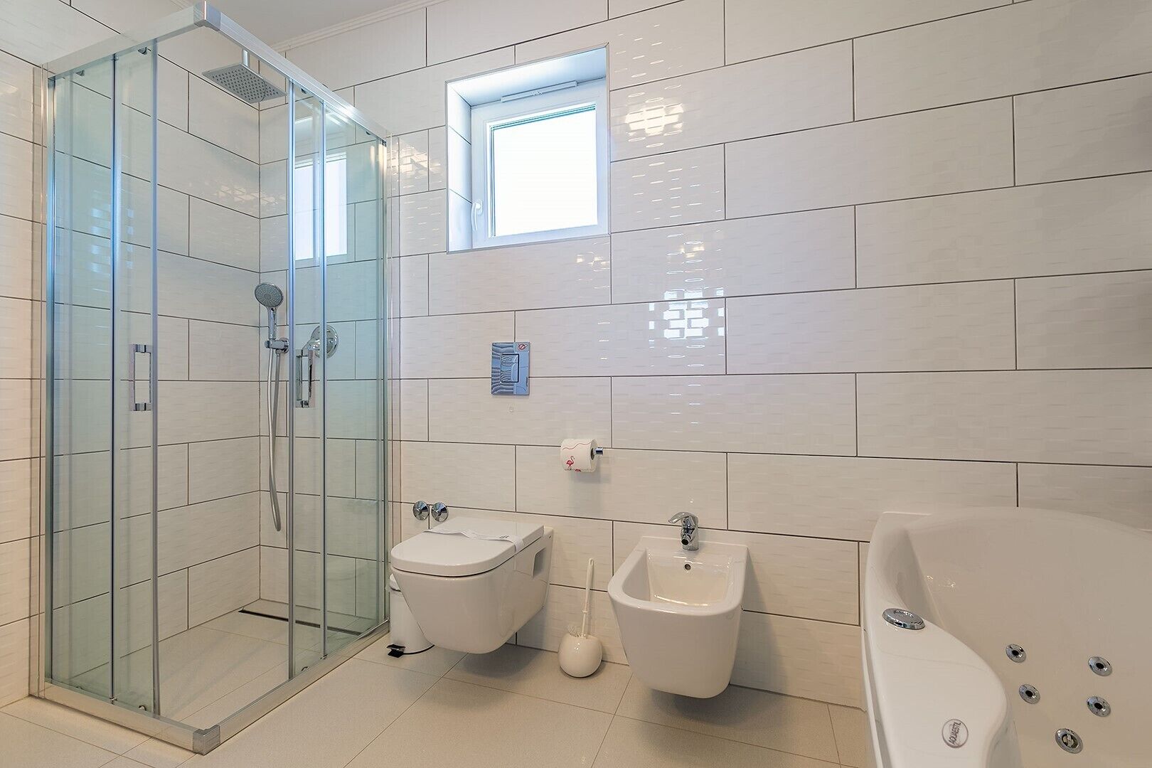 A modern bathroom with a glass-enclosed shower, a toilet, a bidet, and a bathtub.