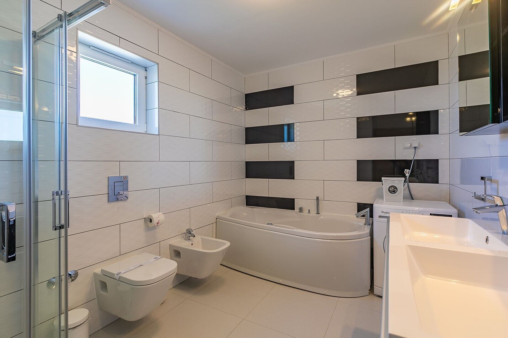 A modern bathroom with a glass shower enclosure, a freestanding bathtub, a toilet, and a sink.