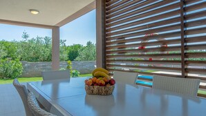 An outdoor dining area with a table, wicker chairs, and a fruit basket. - Villa Stefanja in Galizana (Galizana)