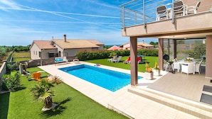 A modern house with a swimming pool, outdoor seating, and a view of neighboring houses. - Villa Stefanja in Galizana (Galizana)