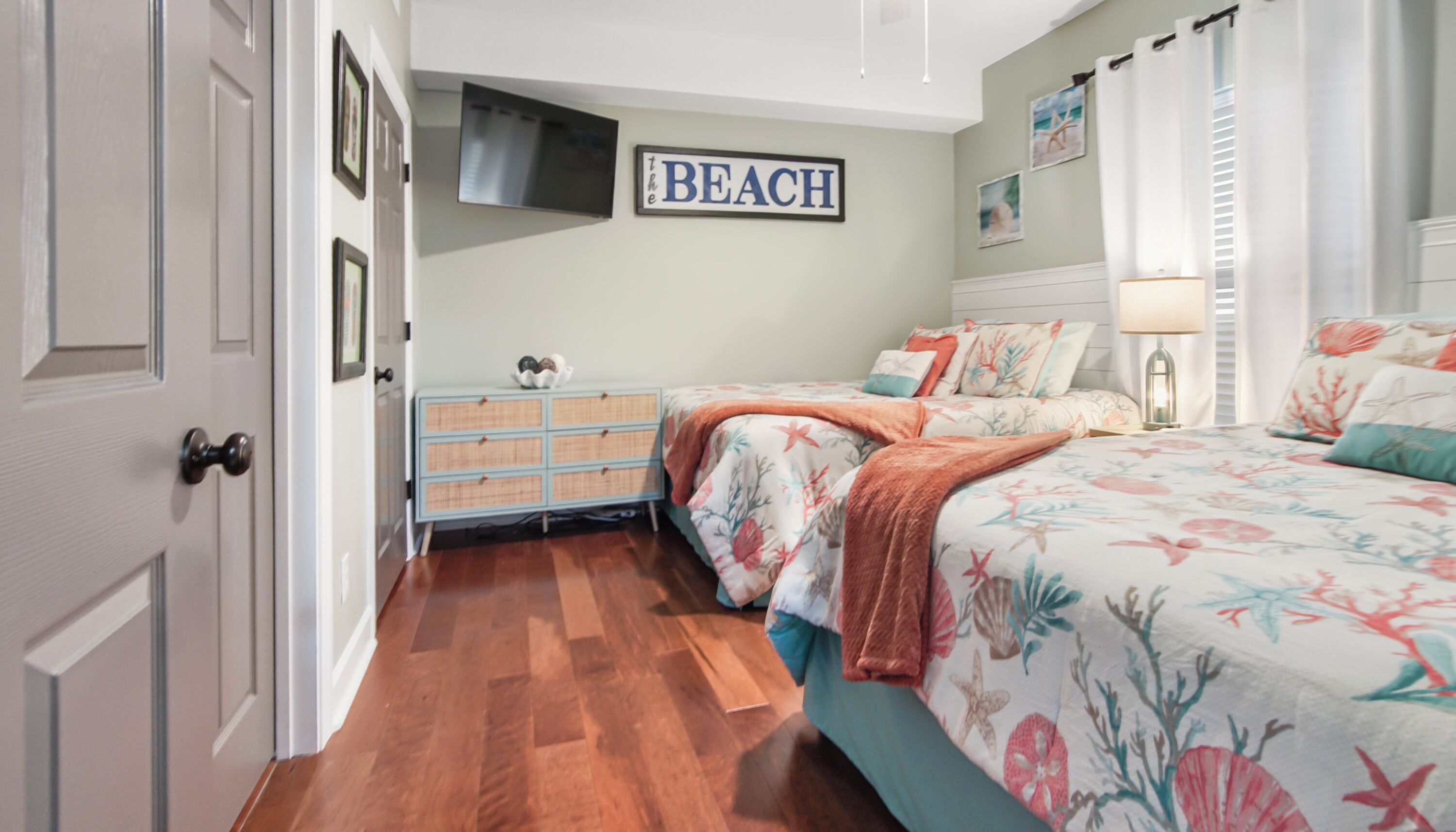 A bedroom with a bed, dresser, and a wall sign reading 'BEACH'.