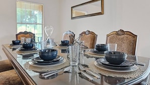 Une table à manger dressée avec des assiettes, des bols et des couverts, entourée de chaises à motifs.