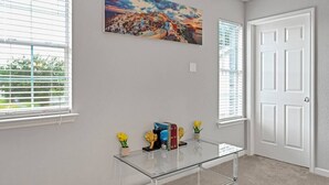 Une pièce avec une table basse en verre, un tableau au mur et une porte.