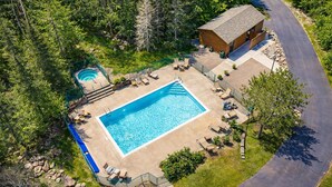 En rektangulär swimmingpool med ett litet bubbelbad, omgiven av solstolar och ett trädäck.