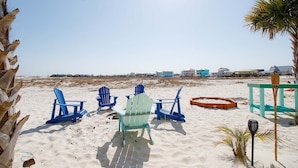 A beach with blue chairs, a wooden deck, and a palm tree. - Starfish Waterfront Family Retreat, Steps to Sound (Navarre)