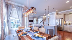 A modern kitchen with stainless steel appliances, a dining area with a wooden table, and a staircase leading to an upper level. - Starfish Waterfront Family Retreat, Steps to Sound (Navarre)