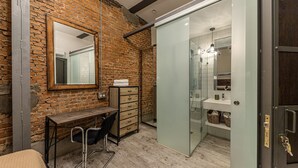 Ein modernes Badezimmer mit Duschkabine aus Glas, einem Holztisch und einem Spiegel.