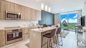 A modern kitchen with a built-in microwave, oven, and bar area with stools.