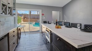 A modern kitchen with a marble countertop, built-in appliances, and a view of a swimming pool. - Pool and Spa + Close to Disney +Game Room (Anaheim)