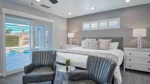 A bedroom with a bed, two chairs, a small table, and a ceiling fan. - Pool and Spa + Close to Disney +Game Room (Anaheim)