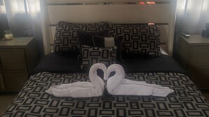 A hotel room with a bed featuring a geometric patterned bedspread, two pillows, and a decorative swan towel arrangement on the bed. - Exclusive and spacious house in Guaynabo (Guaynabo)