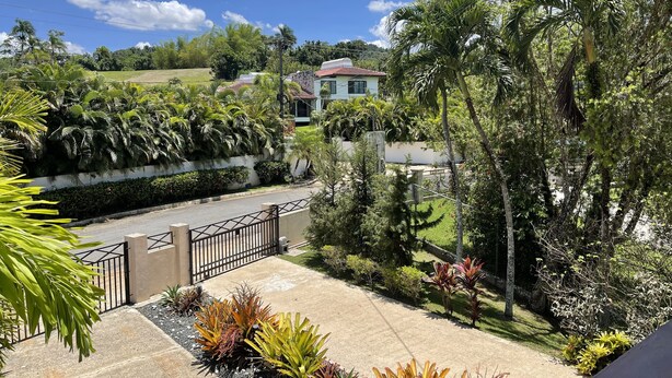A residential area with a house, lush greenery, and a paved driveway. - Exclusive and spacious house in Guaynabo (Guaynabo)