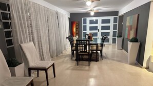 A dining area with a glass table and chairs, a ceiling fan, and a view of a room with a door and artwork. - Exclusive and spacious house in Guaynabo (Guaynabo)