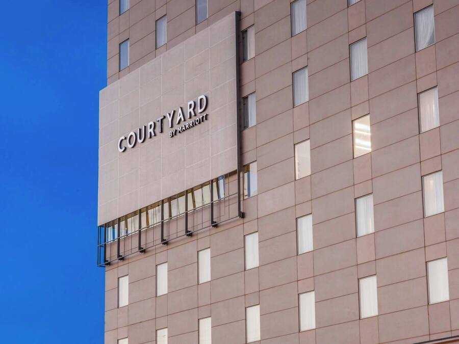 A modern hotel with a large sign reading "COURTYARD BY MARRIOTT". It features a clean, rectangular facade with evenly spaced windows and a flat roof.