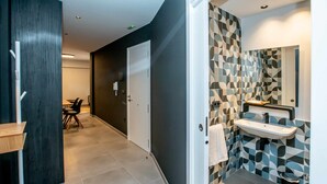 A modern bathroom with a geometric tile backsplash, a white sink, and a dark floor. - Mocho-rural -home Adaptado (Beceite)