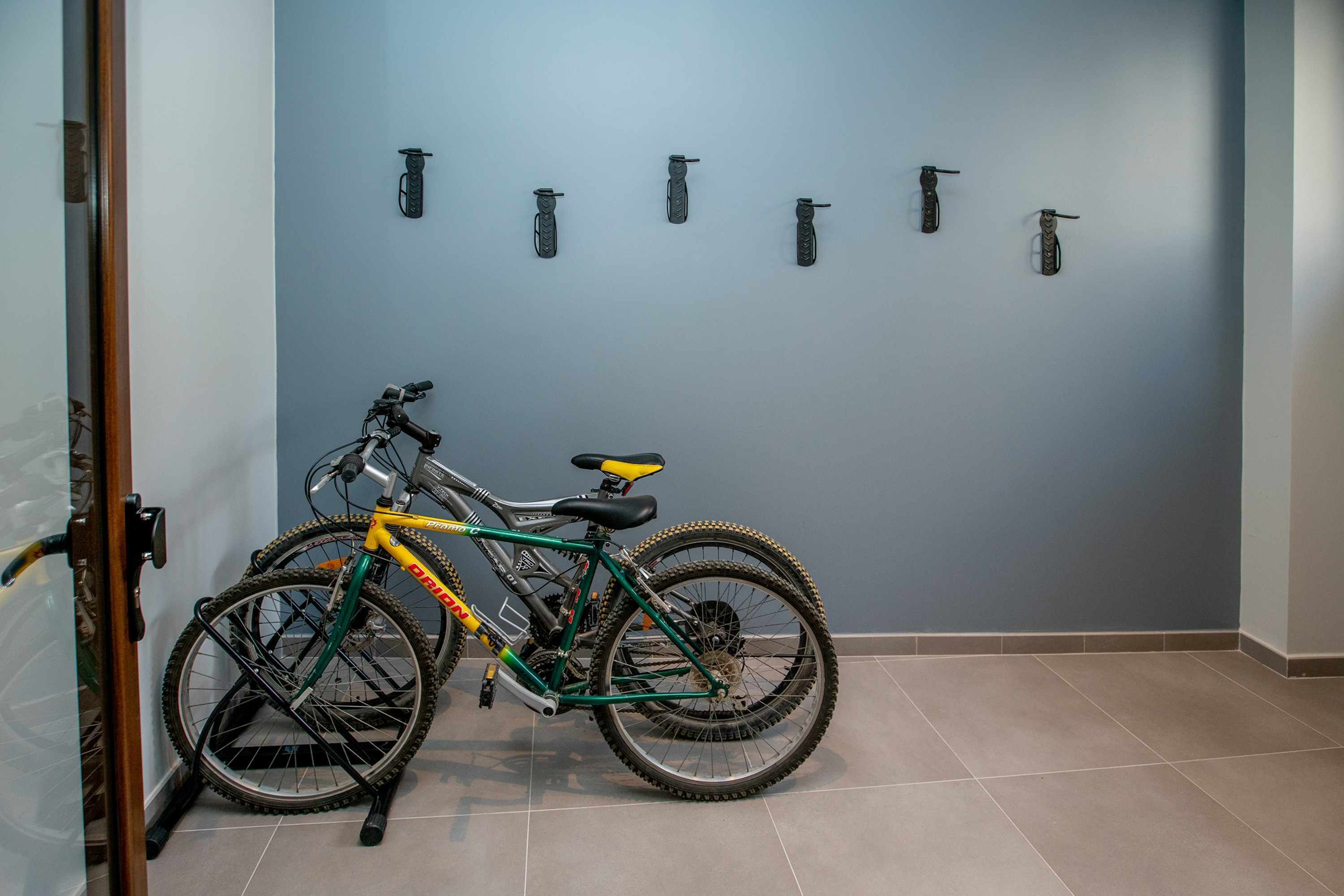 A room with a bicycle leaning against a wall, a door, and a tiled floor.