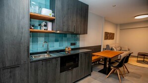 A modern kitchen with dark wood cabinets, a built-in dishwasher, and a blue tiled backsplash. - Mocho-rural -home Adaptado (Beceite)
