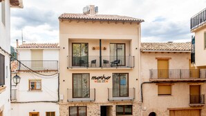A two-story building with balconies, a sign reading "mocho rural home," and a stone facade. - Mocho-rural -home Adaptado (Beceite)