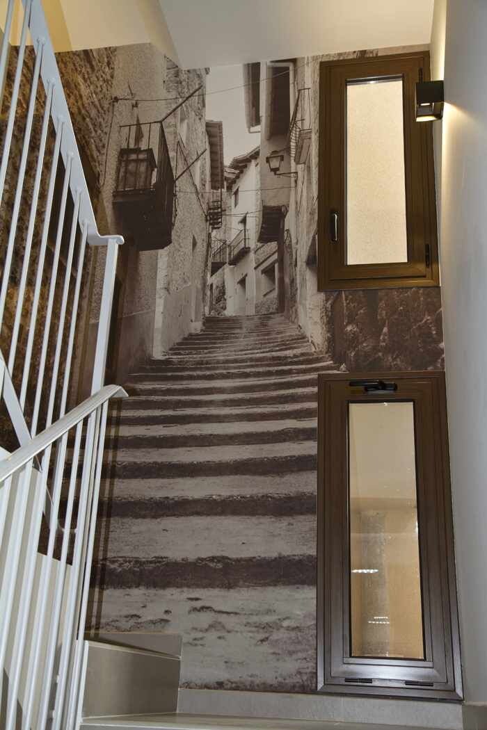 Una scala con un murale raffigurante una scena di strada, una ringhiera bianca e una porta con un pannello di vetro.