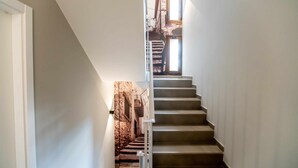 Un escalier offrant une vue sur un bâtiment en pierre, visible à travers une fenêtre.