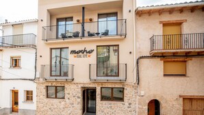 Un bâtiment à deux étages, doté d’une façade en pierre, de balcons avec des garde-corps en métal et d’une enseigne indiquant « Résidence rurale ».
