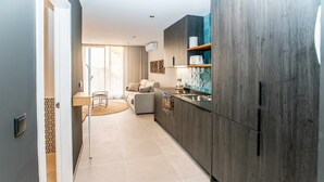 A modern kitchen with dark wood cabinets, a built-in oven, and a sink. There is a dining area with a round table and chairs. - Mocho- Rural- Home Villanueva A (Beceite)