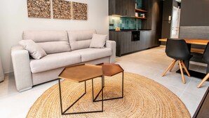 A modern living room with a sofa, a coffee table, and a dining area with chairs. - Mocho- Rural- Home Villanueva A (Beceite)