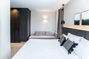 A modern hotel room with a large bed, a sofa, a wall-mounted light, and a painting. - Mocho-rural-home Lonja B (Beceite)