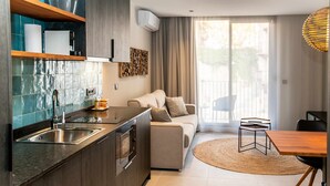 A modern kitchen with a built-in oven, a sink, and a countertop. There is a dining area with a table and chairs, and a sofa with a rug. - Mocho-rural-home Lonja B (Beceite)