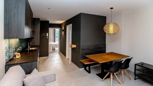 A modern kitchen with dark cabinetry, a wooden dining table, and black chairs. - Mocho-rural-home Lonja A (Beceite)