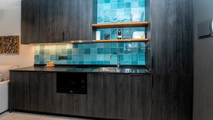 A modern kitchen with dark wood cabinetry, a stainless steel sink, and blue-tiled backsplash. - Mocho-rural-home Lonja A (Beceite)
