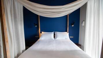 A bed with white bedding, draped white curtains, and two bedside lamps.