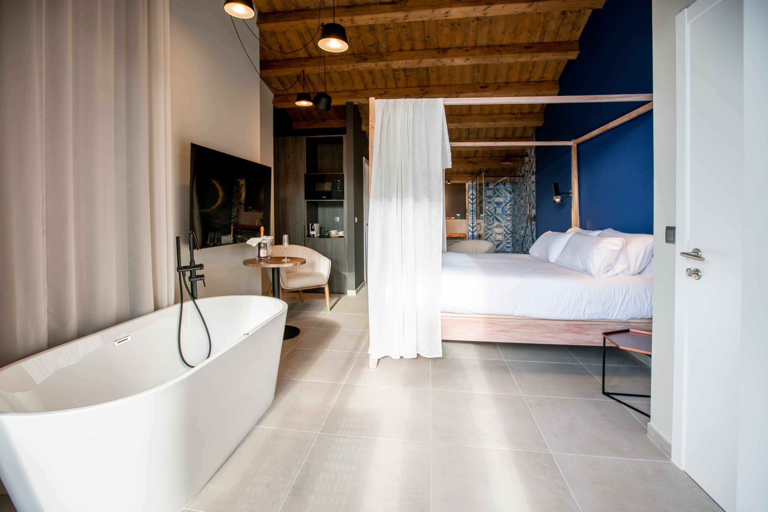 Un baño moderno con una bañera independiente, un espejo grande y techo de madera.