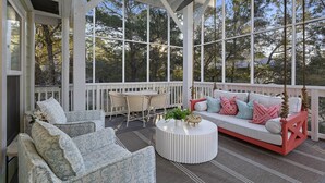 A covered porch with a white railing, a ceiling fan, a round white table, and a red and white sofa with patterned cushions. - Dune Betty - 30A, Heated Private Pool, Walk to the Beach + Restaurants! (Santa Rosa Beach)