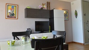 Una cucina moderna con un tavolo da pranzo, sedie, un frigorifero e una televisione.