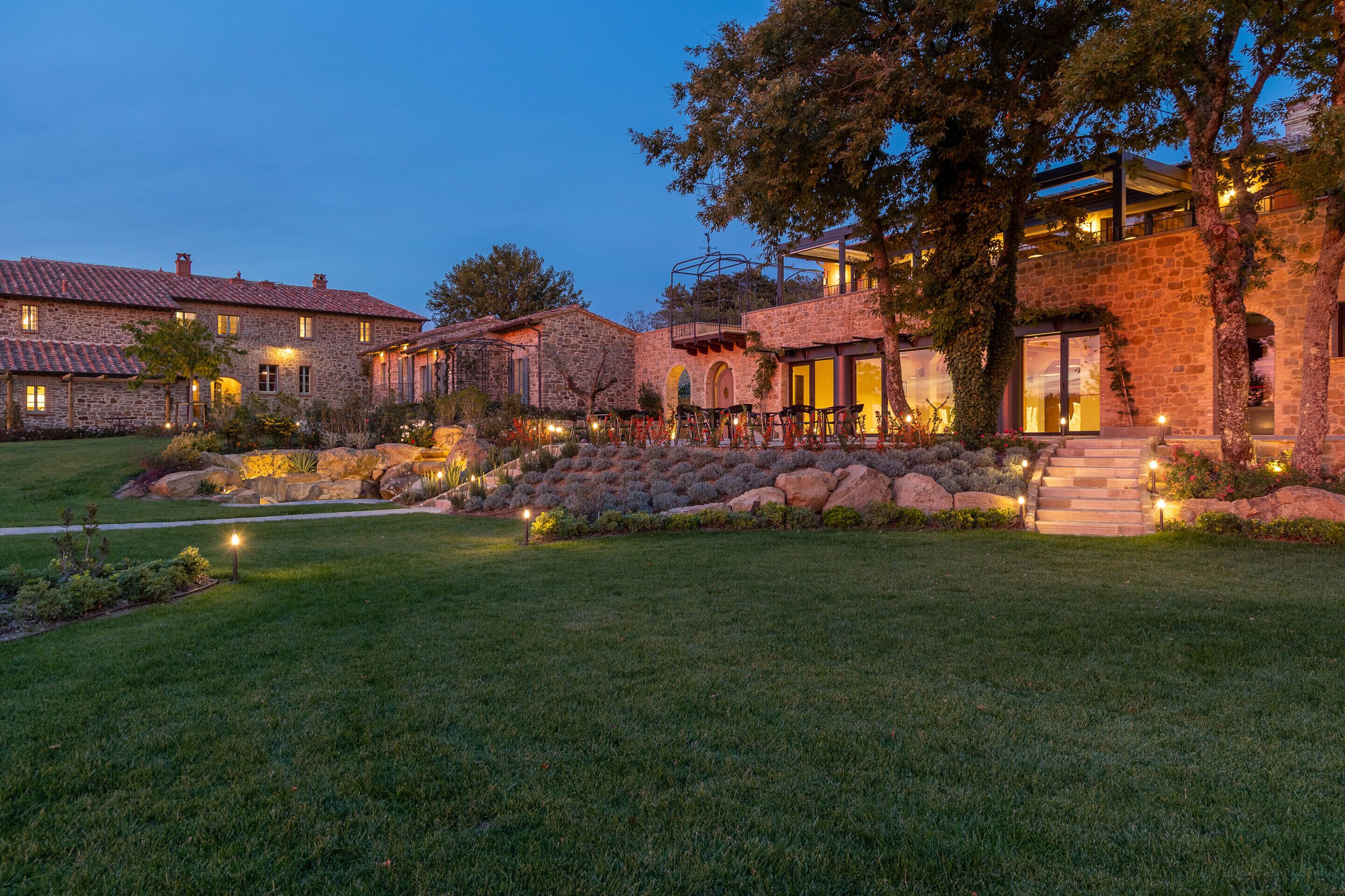 A multi-story stone building with a well-maintained lawn and outdoor seating area.