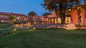 A multi-story stone building with a well-maintained lawn and outdoor seating area.