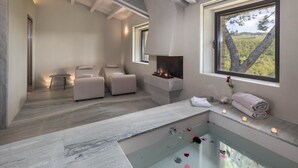 Un spa moderno con una bañera de hidromasaje con cerramiento de vidrio, chimenea y vistas al exterior.