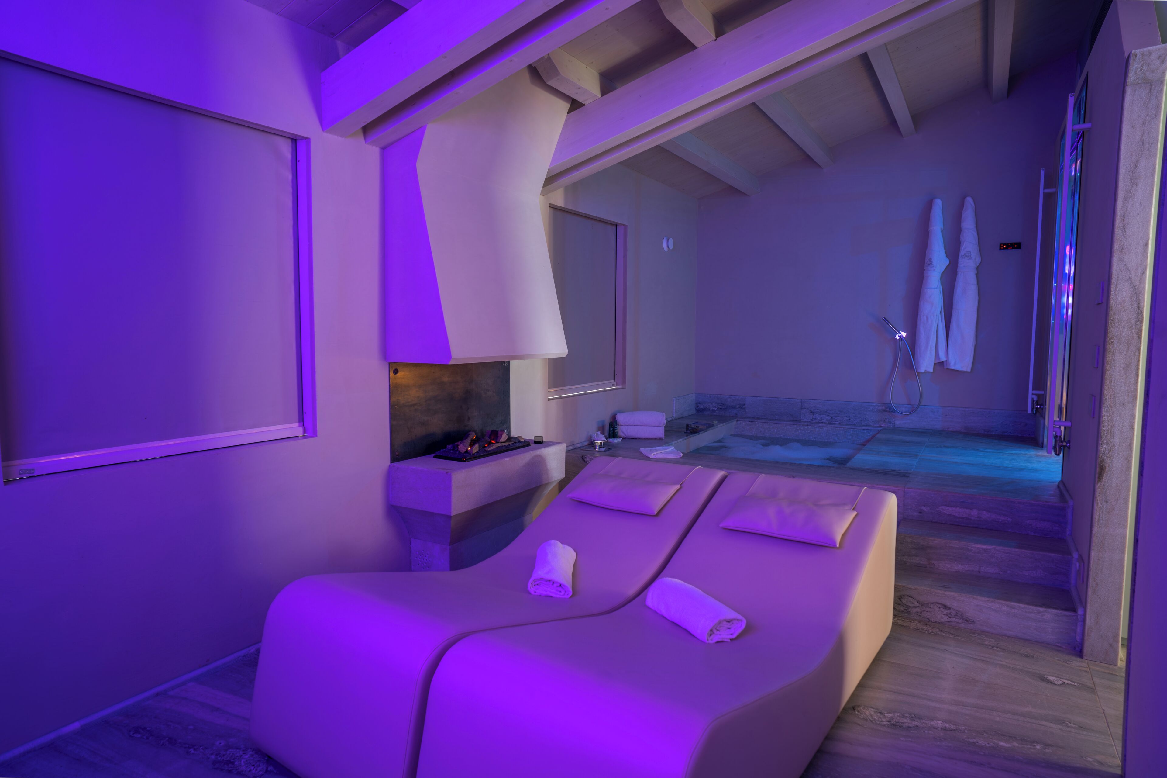 Um quarto de spa com mesa de massagem, uma mesinha com velas e vista para a área da piscina.