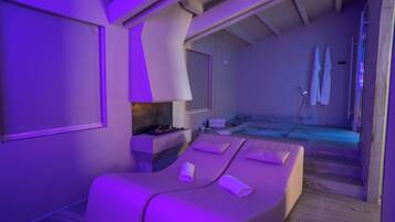 Um quarto de spa com mesa de massagem, uma mesinha com velas e vista para a área da piscina.