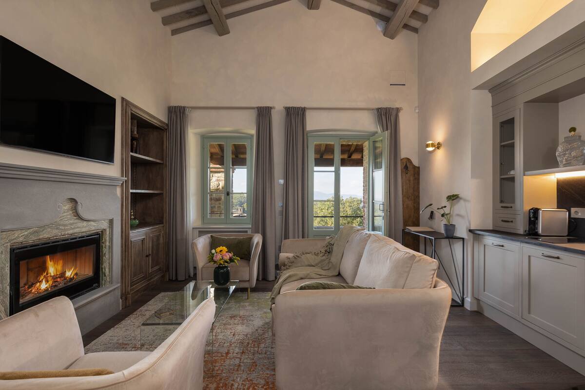 Una sala de estar acogedora con chimenea, asientos cómodos y vistas al exterior.