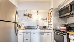 Een moderne keuken met witte kasten, roestvrijstalen apparatuur en diverse keukengerei aan de wand.